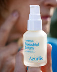 Luminous Bakuchiol Serum Face against a female face in the background.